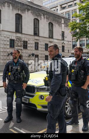 Gli agenti di polizia armati della città di Londra si rompono e si levano in conversazione accanto all'auto di polizia parcheggiata in Wood Street, Londra, Inghilterra, Regno Unito Foto Stock