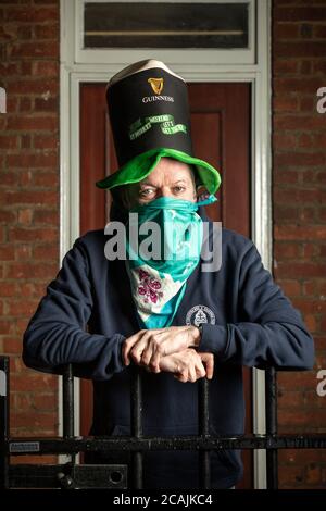 Un uomo in un cappello Guinness che si trova all'ingresso della sua casa durante il blocco COVID-19, Stockwell, Londra Foto Stock