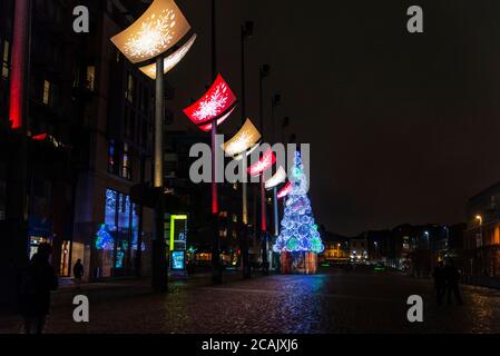 Dublino, Irlanda - 30 dicembre 2019: Piazza Smithfield di notte con un grande abete con decorazione e luci di Natale e la gente intorno al ce Foto Stock