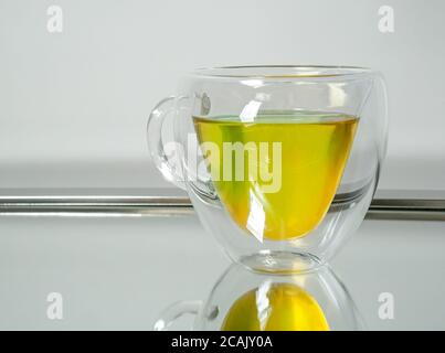 Una teiera di vetro di tè caldo alle erbe riflessa su a. speculare Foto Stock