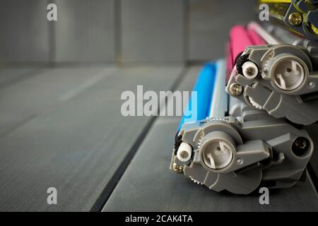 Vista laterale delle cartucce di inchiostro del toner per un laser da ufficio stampante su sfondo grigio in legno Foto Stock