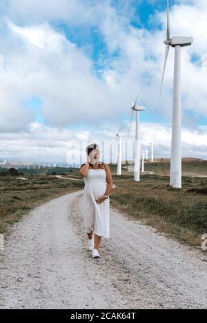 Donna che cammina in una fattoria di turbine eoliche in Galizia, Spagna Foto Stock