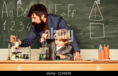 Insegnante uomo con little boy. La scuola le attrezzature di laboratorio. studente facendo esperimenti scientifici con microscopio in laboratorio. Si torna a scuola. il padre e il figlio a scuola. usando microscopio in laboratorio. Vivere in epoca digitale. Foto Stock