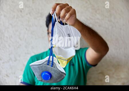 Il maschio adulto può contenere tre diversi tipi di respiratori a mezza faccia davanti al viso. Il modello è in background fuori fuoco Foto Stock
