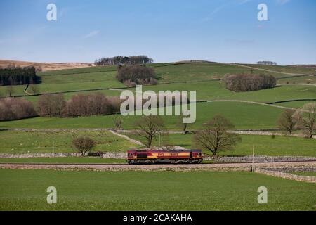 DB Cargo classe 66 in inglese gallese e ferrovia scozzese livrea motore leggero lungo la linea di trasporto Rylstone nelle valli dello Yorkshire Foto Stock