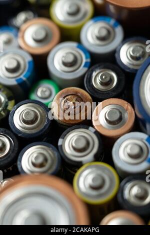 Primo piano delle estremità positive delle batterie scariche di diversi formati e dimensioni, messa a fuoco selettiva. Batteria usata con corrosione e ruggine. Pericolo gar Foto Stock