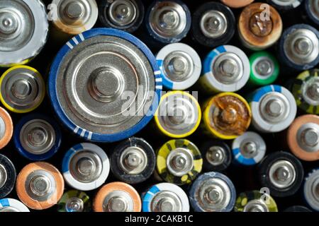 Primo piano delle estremità positive delle batterie scariche di diversi formati e dimensioni, messa a fuoco selettiva. Batteria alcalina usata con corrosione e ruggine. Haza Foto Stock