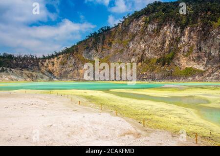 I depositi di zolfo giallo e il lago blu di Kawah Putih, Giava, Indonesia Foto Stock