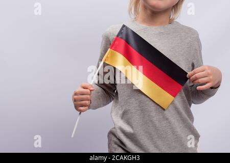 Bambino detiene una bandiera tedesca. Primo piano. Istruzione scolastica in Germania. Studio della lingua tedesca. Foto Stock