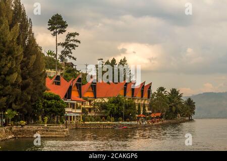 Una fila di case e ville Bataknese sulla riva del lago Toba, Sumatra settentrionale, indonesia Foto Stock