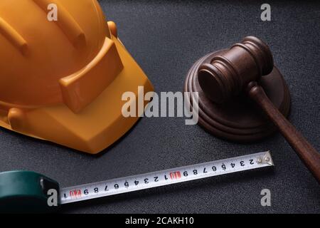 Gavel giudice in legno, casco giallo da costruzione e nastro. Concetto di legge sulla costruzione. Concetto di legge sul lavoro. Foto Stock
