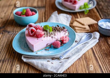 Cheesecake di lampone rinfrescante senza cottura, condito con frutti di bosco freschi, servito su un piatto di ceramica Foto Stock