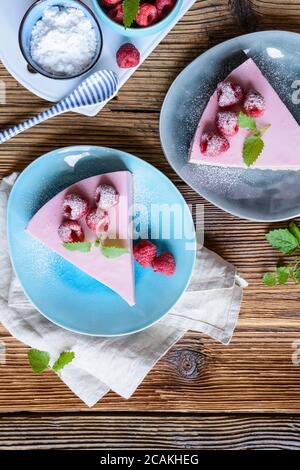 Cheesecake di lampone rinfrescante senza cottura, condito con frutti di bosco freschi, servito su un piatto di ceramica Foto Stock