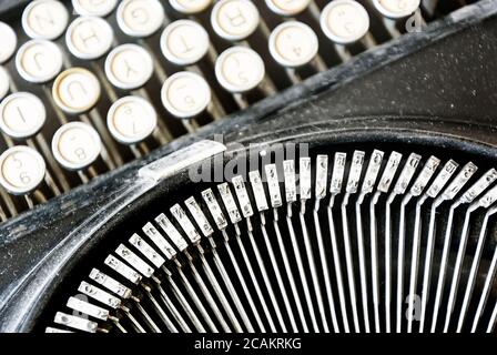 i martelli da ferro di una vecchia macchina da scrivere con i tasti sfocati sullo sfondo. Tipizzazione e tecnologia obsoleta. Oggetto vintage Foto Stock