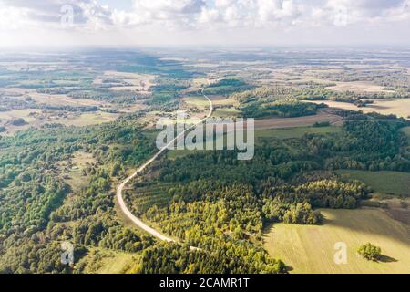 vista panoramica aerea del paesaggio rurale con campi verdi, foresta e cielo blu con nuvole soffici all'orizzonte Foto Stock