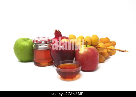 Rosh Hashanah, Capodanno ebraico, simboli tradizionali, Miele in un vaso di vetro, melograni, datteri, mele rosse e verdi. Isolato su sfondo bianco Foto Stock