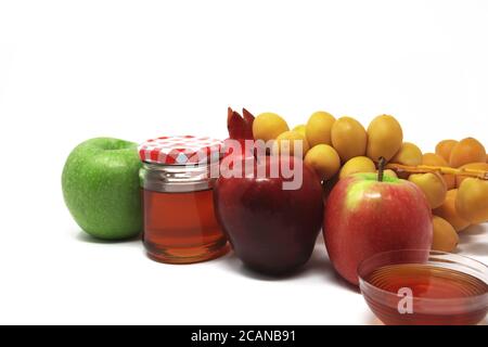 Rosh Hashanah, Capodanno ebraico, simboli tradizionali, Miele in un vaso di vetro, melograni, datteri, mele rosse e verdi. Isolato su sfondo bianco Foto Stock