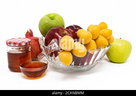 Rosh Hashanah, Capodanno ebraico, simboli tradizionali, Miele in un vaso di vetro, melograni, datteri, mele rosse e verdi. Isolato su sfondo bianco Foto Stock