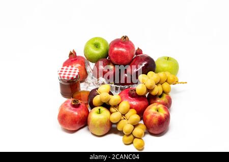 Rosh Hashanah, Capodanno ebraico, simboli tradizionali, Miele in un vaso di vetro, melograni, datteri, mele rosse e verdi. Isolato su sfondo bianco Foto Stock