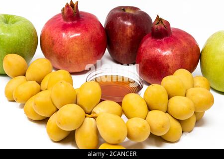 Rosh Hashanah, Capodanno ebraico, simboli tradizionali, Miele in un vaso di vetro, melograni, datteri, mele rosse e verdi. Isolato su sfondo bianco Foto Stock
