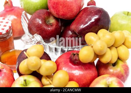 Rosh Hashanah, Capodanno ebraico, simboli tradizionali, Miele in un vaso di vetro, melograni, datteri, mele rosse e verdi. Isolato su sfondo bianco Foto Stock