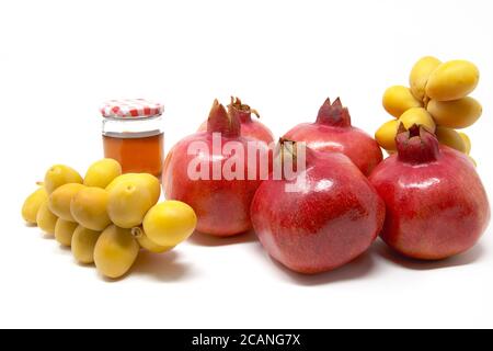 Rosh Hashanah, Capodanno ebraico, simboli tradizionali, Miele in un vaso di vetro, melograni, datteri. Isolato su sfondo bianco Foto Stock