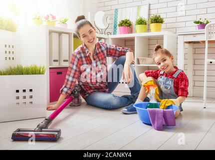 La famiglia è felice di pulire la camera. Madre e figlia fanno la pulizia in casa. Una giovane donna e una bambina spazzarono la polvere e aspirarono il Foto Stock