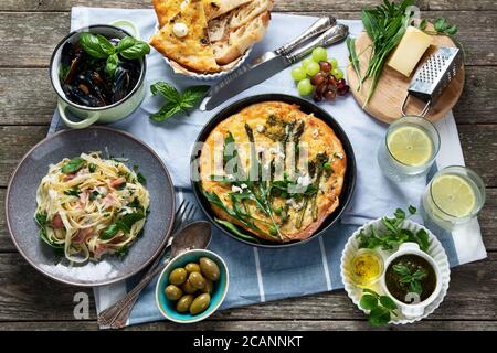 Appetitosa cucina italiana classica su tavolo rustico in legno. Diversi tipi di pizza, pasta, spuntini e caprezze. Cibo sano fatto in casa. Foto Stock