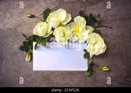 Rose bianche con biglietto d'auguri su sfondo in marmo. Lettera d'amore romantica per San Valentino o concetto di festa della mamma Foto Stock
