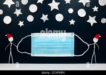 Bastone uomo figura indossando cappello di santa tenendo una maschera con stelle d'argento e sfere ornamento sfondo. Concetto sicuro di Natale. Foto Stock