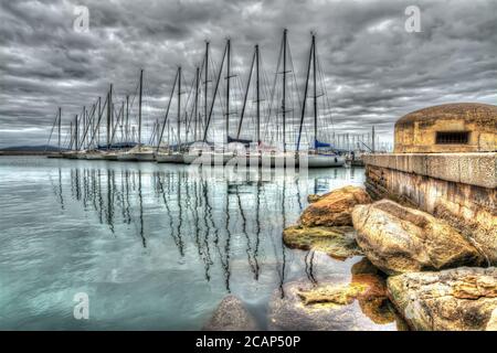 Vecchio bunker nel porto di Alghero sotto un cielo drammatico. Elaborato per l'effetto di mappatura dei toni hdr Foto Stock