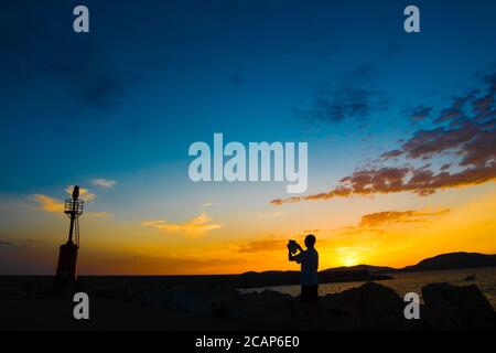 tourist scatta una foto ad Alghero al tramonto Foto Stock