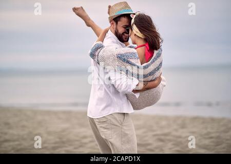 ragazzo caucasico che porta la sua fidanzata tra le braccia in spiaggia Foto Stock