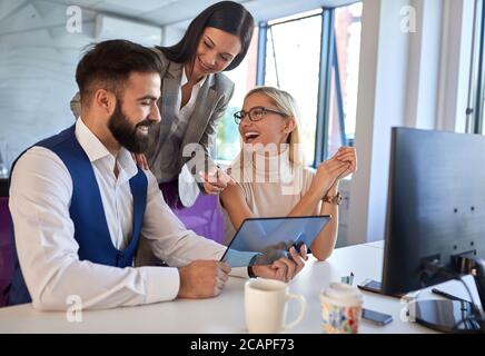 Giovani colleghi che testano dispositivi hi-tech in ufficio Foto Stock