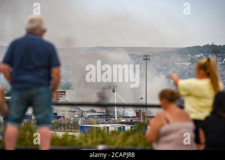 Newhaven UK 8 agosto 2020 - la gente guarda da una collina vicina come il fumo sale sopra Newhaven Port East Sussex mentre i pompieri combattono una boccata in una fabbrica vicino alla stazione ferroviaria: Credit Simon Dack / Alamy Live News Foto Stock