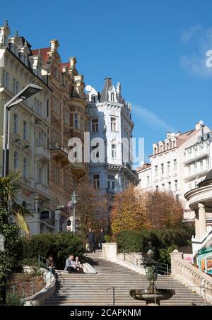 Karlovy Vary Repubblica Ceca ottobre 28 2019. Due facce Janus-scultura allegorica con gocce di acqua minerale calda. Scalinata ai cottage. Foto Stock