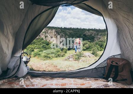 Giovane coppia in campeggio in una tenda in montagna che domina canyon roccioso. Foto Stock