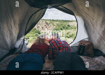 Giovane coppia in campeggio in una tenda in montagna che domina canyon roccioso. Foto Stock