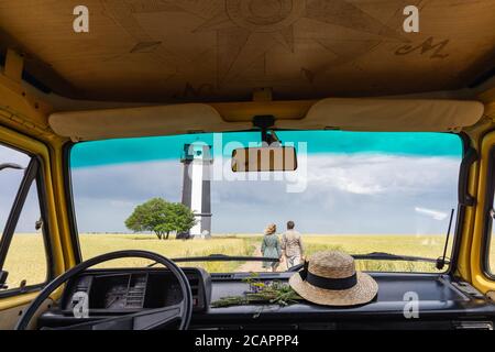 Giovane coppia dell'Europa orientale che viaggia in un camper giallo attraverso la campagna. Campeggio off-grid auto-costruito in campeggio nella natura selvaggia. Foto Stock