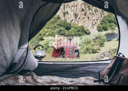 Giovane coppia in campeggio in una tenda in montagna che domina canyon roccioso. Foto Stock