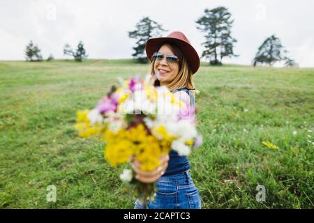 Giovane donna con bouquet di fiori sul campo Foto Stock