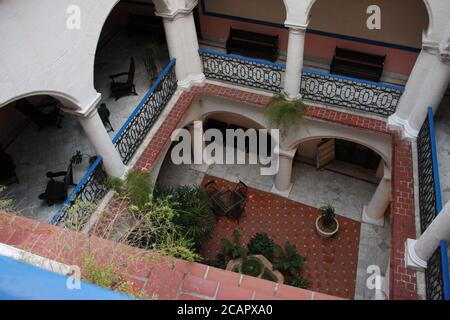 Cortile interno all'aperto, in stile coloniale, rosso, rosa e bianco; Hotel Santa Isabel, l'Avana, Cuba Foto Stock