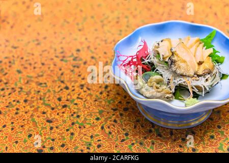 Sashimi crudi alta cucina giapponese di Awabi fresco abalone in un piatto con alghe rosse Gracilaria, foglie di shiso e julienne di rafano daikon A. Foto Stock