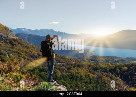Il viaggiatore con uno zaino e uno smartphone si alza su uno montagna Foto Stock