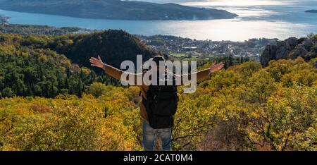 Un viaggiatore con uno zaino si erge sulla parte superiore di la montagna Foto Stock