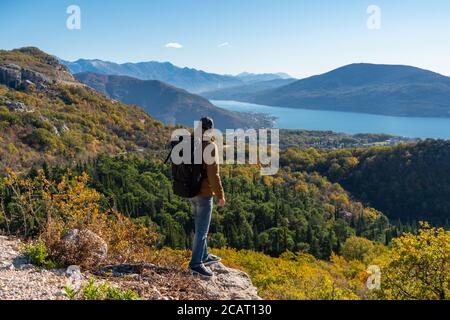 Un viaggiatore con uno zaino si erge sulla parte superiore di la montagna Foto Stock