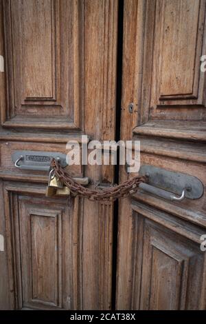 Scatto verticale di due vecchie porte di legno a metà apertura bloccate con una catena in acciaio Foto Stock