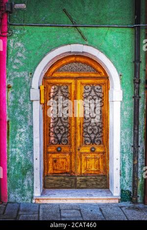 Porta in legno in una verde parete rustica a Burano, Italia Foto Stock