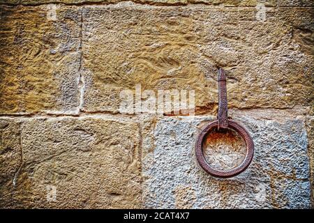 Antico cerchio di ferro appeso su un muro di pietra Foto Stock