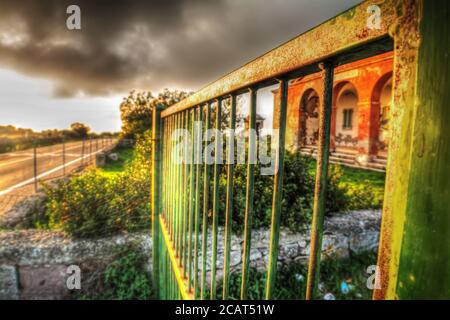 primo piano di un cancello arrugginito sotto un cielo grigio al tramonto Foto Stock